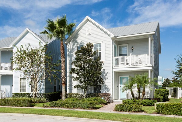 A row of white two-story townhouses with balconies, surrounded by well-maintained lawns and palm trees. - Villa The Nantucket at Patriots Landing 3 Bedroom Reunion (Kissimmee)