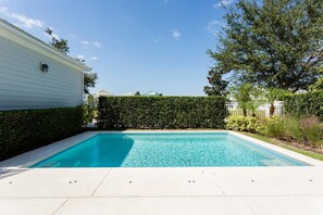 A rectangular swimming pool with clear blue water, surrounded by a white deck and a hedge. - Villa The Nantucket at Patriots Landing 3 Bedroom Reunion (Kissimmee)