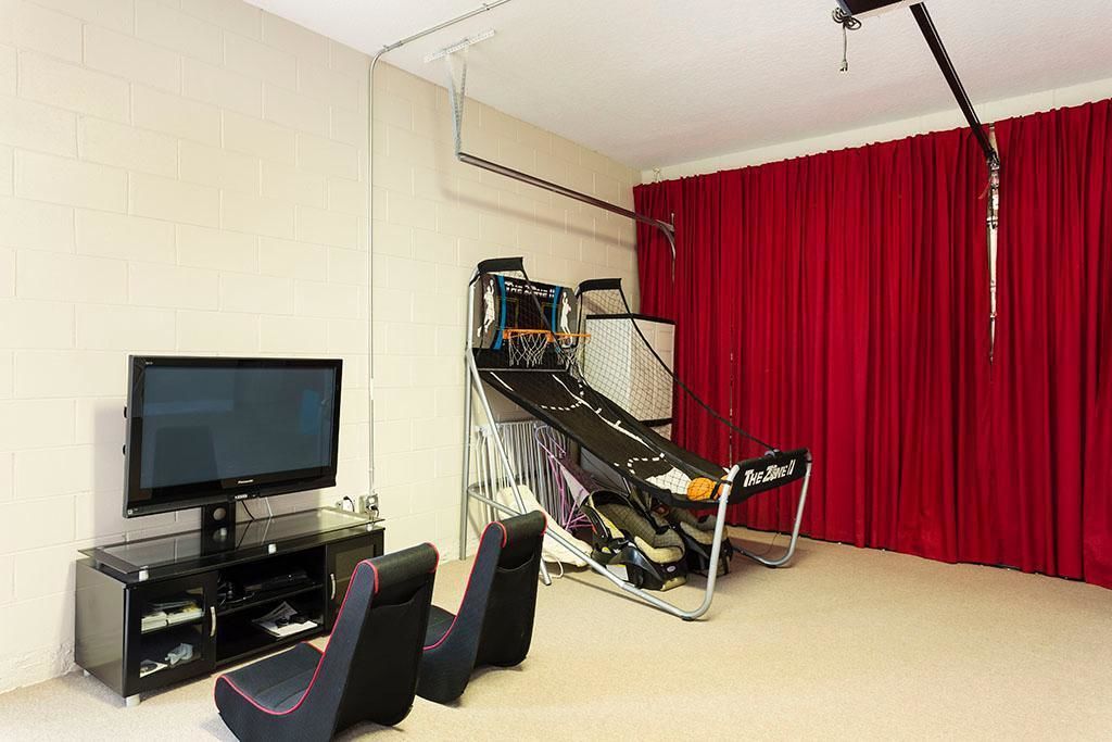 Una habitación con televisión, cinta de correr y una cortina roja.