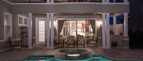 A two-story house with a swimming pool, outdoor seating, and a balcony.