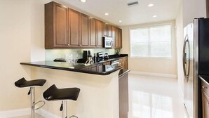 Une cuisine moderne avec des meubles en bois, un plan de travail noir et des appareils électroménagers en acier inoxydable.