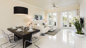 Un espace repas moderne avec une table noire, des chaises transparentes et un ventilateur de plafond.