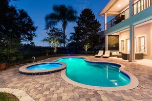 Ein Schwimmbecken mit geschwungener Form, umgeben von einer gepflasterten Terrasse.