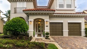 A two-story house with a tiled roof, a front porch, and a garage.