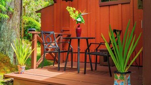 A wooden deck with a table and chairs, surrounded by potted plants and a lantern.