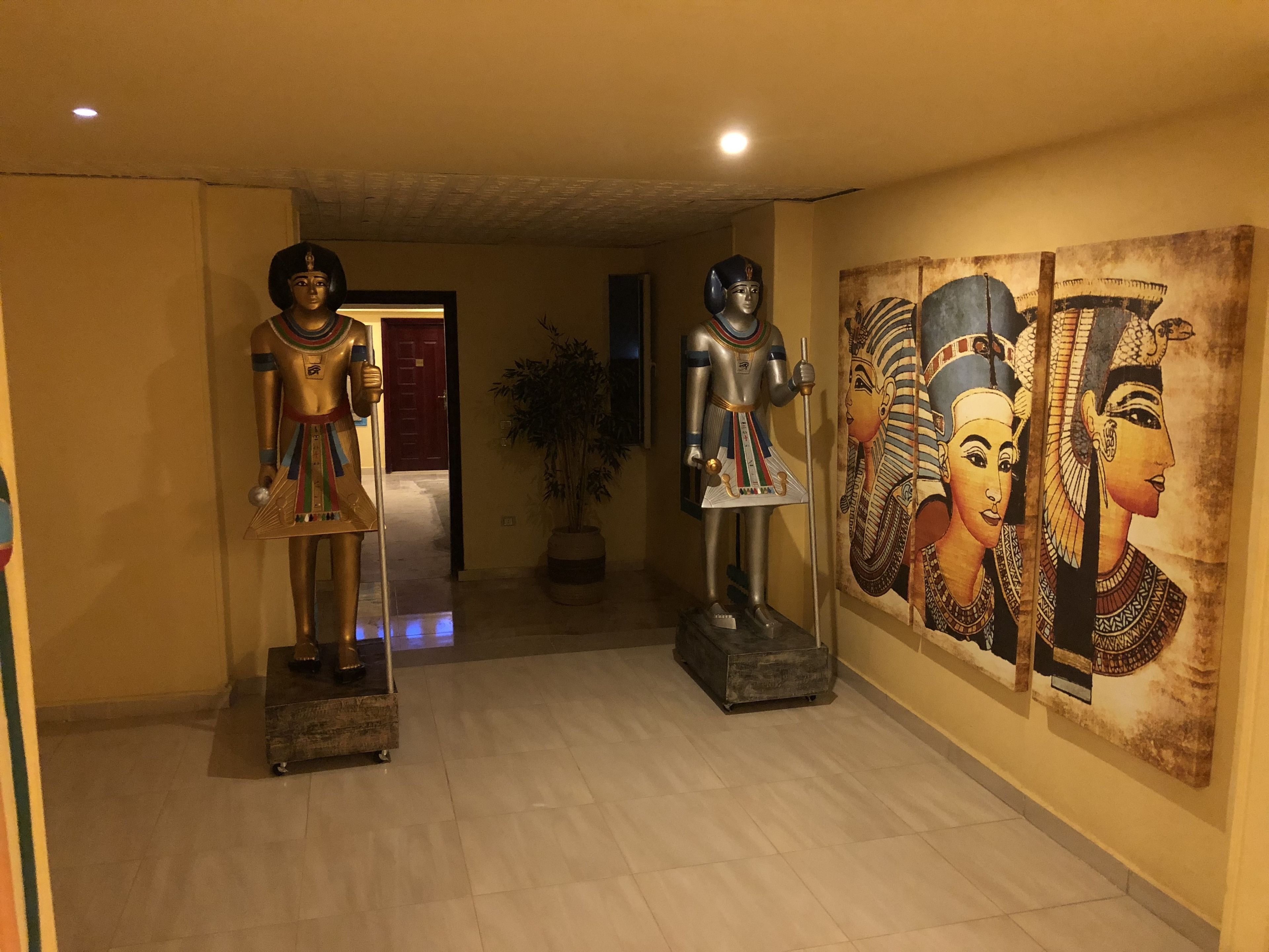 Un pasillo con estatuas egipcias y decoración mural.