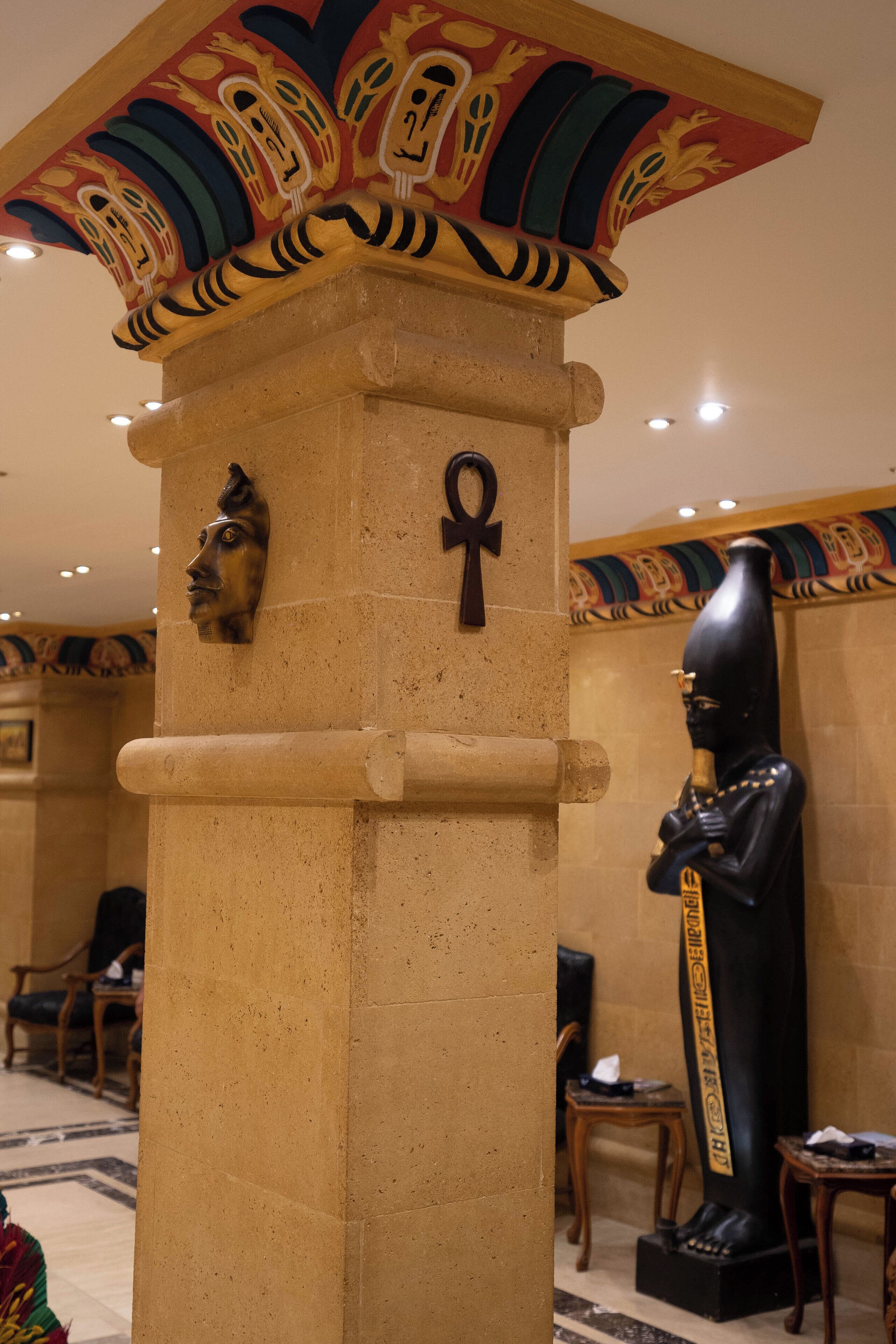 A column with an Egyptian-themed design, including a carved face and an ankh symbol.