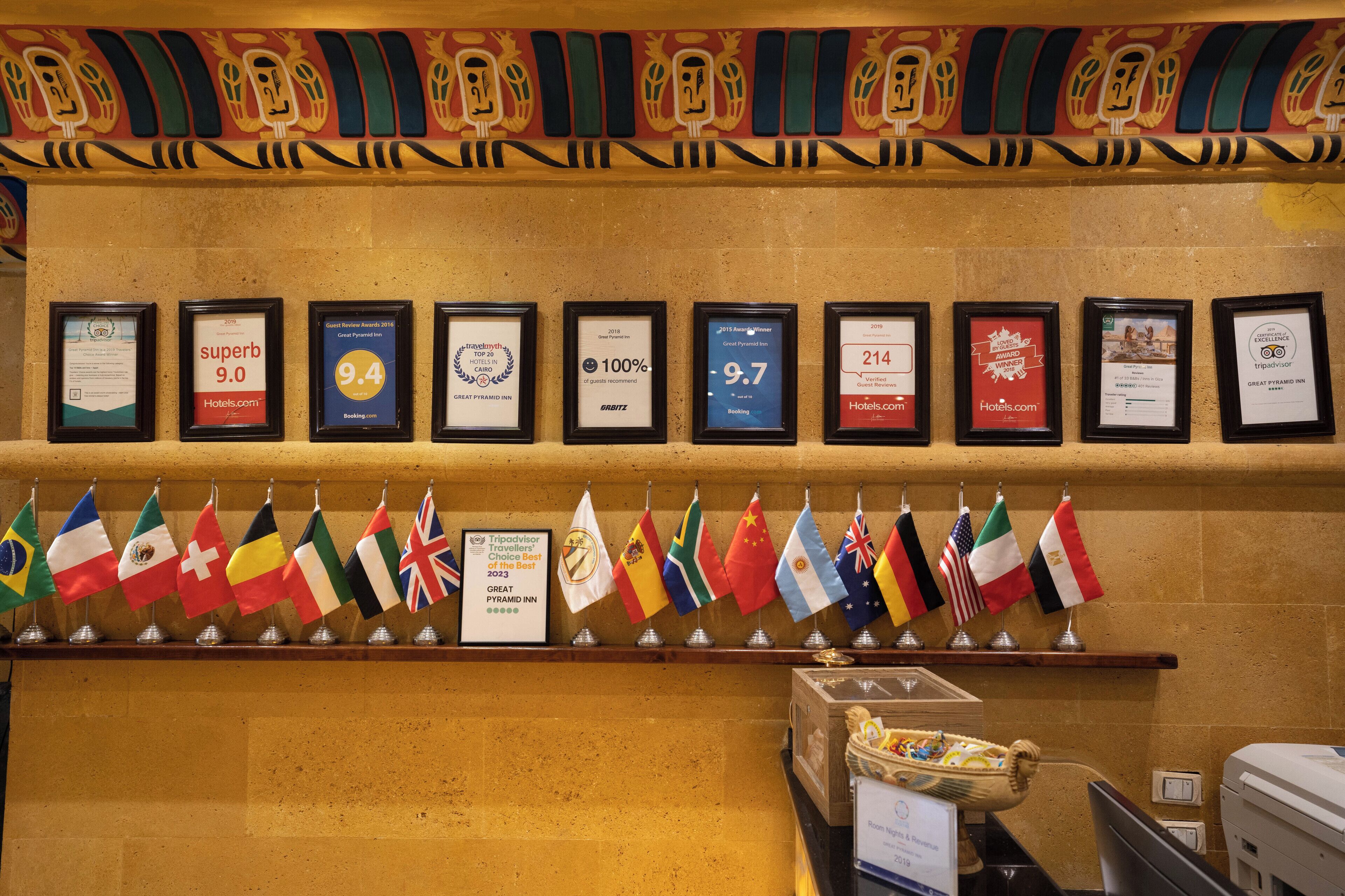 A wall with framed awards and a row of international flags.