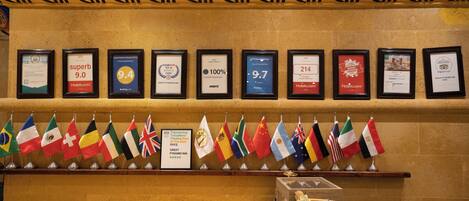 A wall with framed awards and a row of international flags.