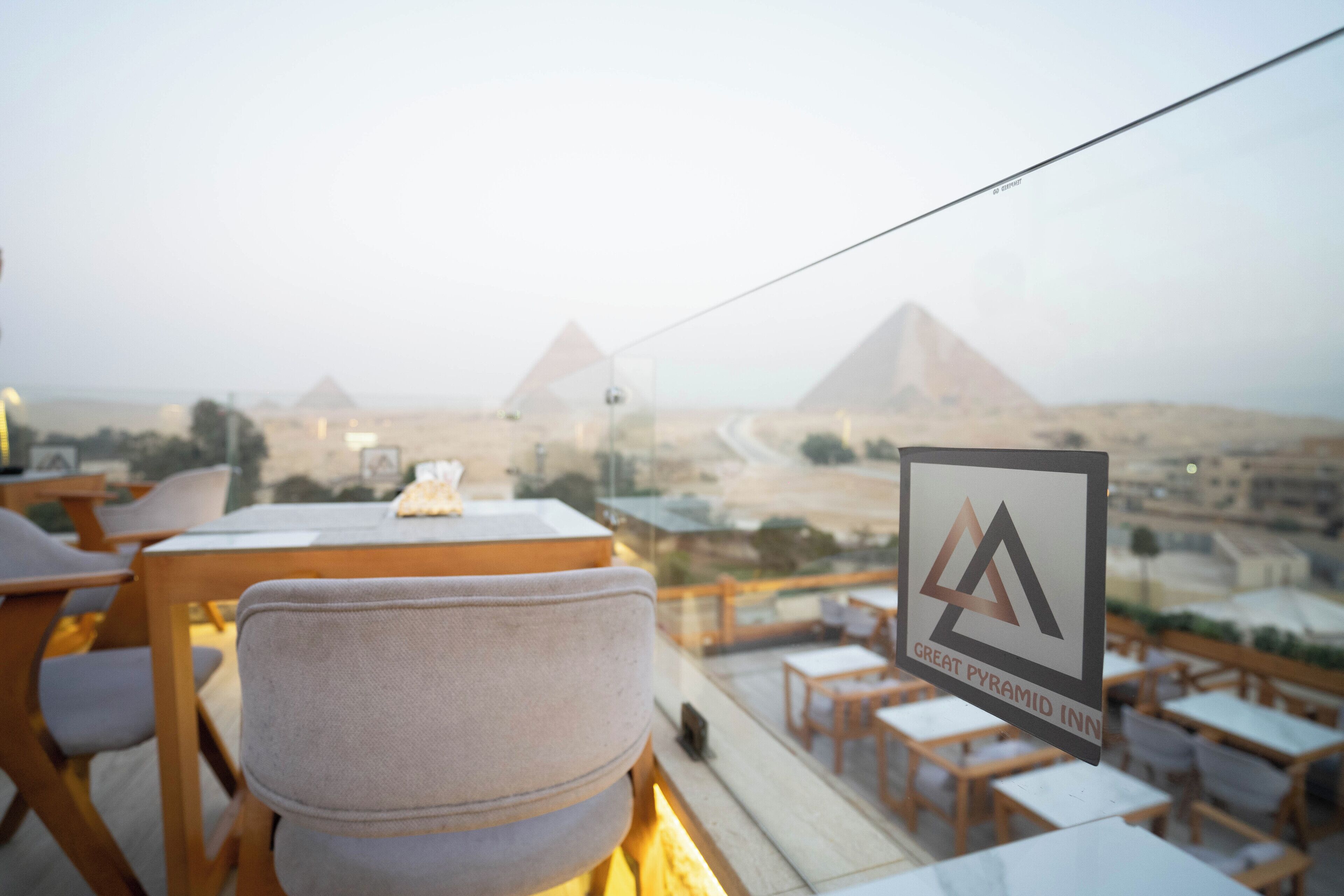 A restaurant with a view of the pyramids, tables, and chairs.