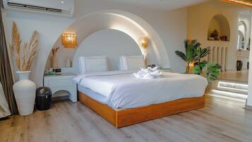 A modern bedroom with a wooden bed, white linens, a nightstand, a lamp, and a potted plant.