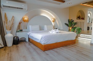 A modern bedroom with a wooden bed, white linens, a nightstand, a lamp, and a potted plant.