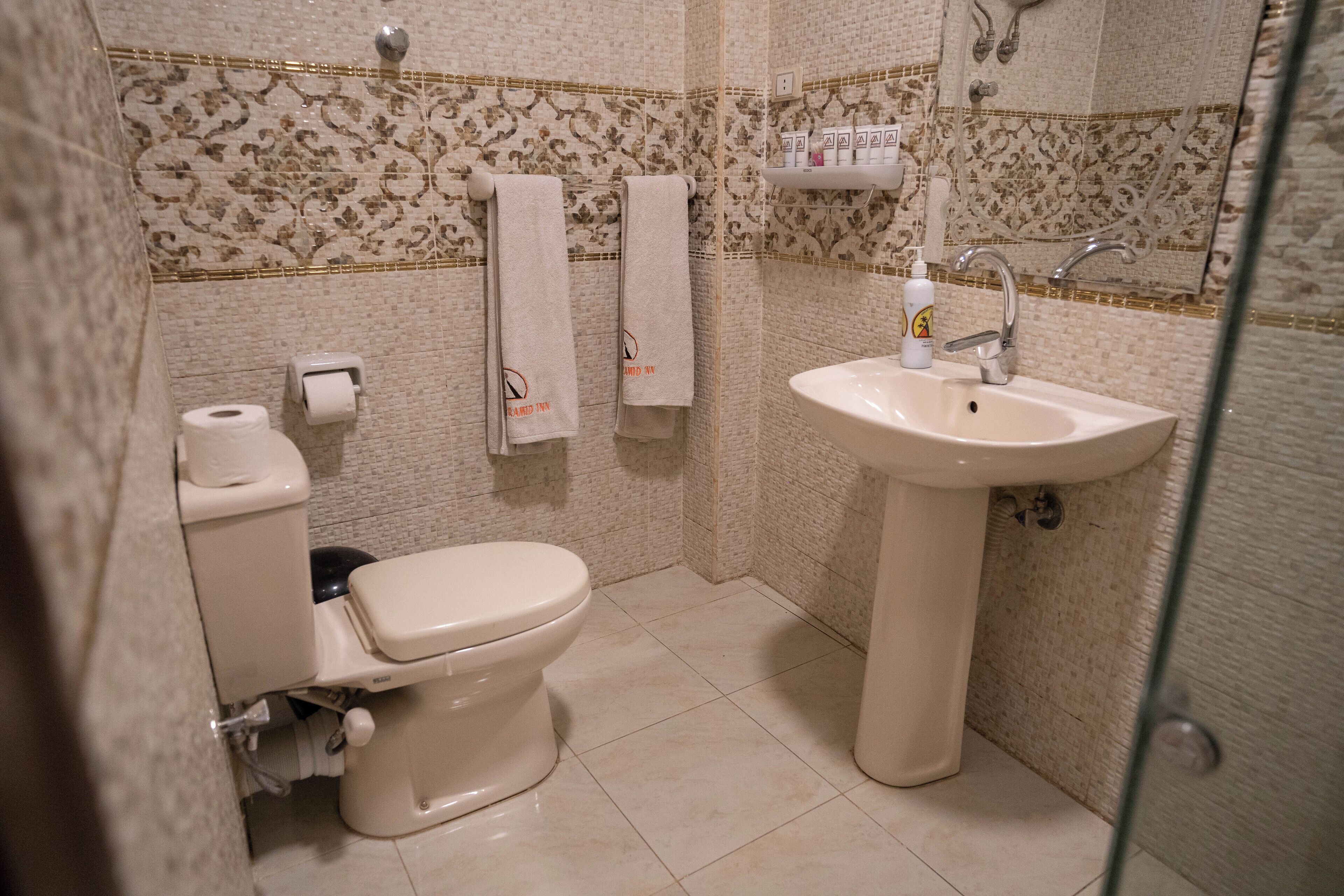 Et badeværelse med toilet, vask og flisebordsmønster.