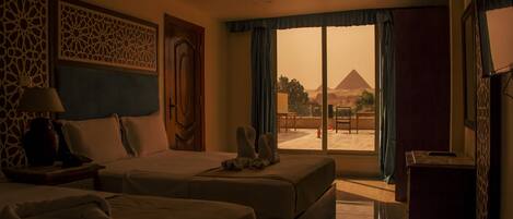 A hotel room with two beds, a view of the pyramid, and a balcony.