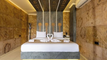 Una habitación de hotel moderna con una cama grande, un detalles en mármol y un diseño de techo singular.