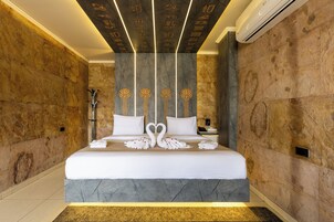 Una habitación de hotel moderna con una cama grande, un detalles en mármol y un diseño de techo singular.