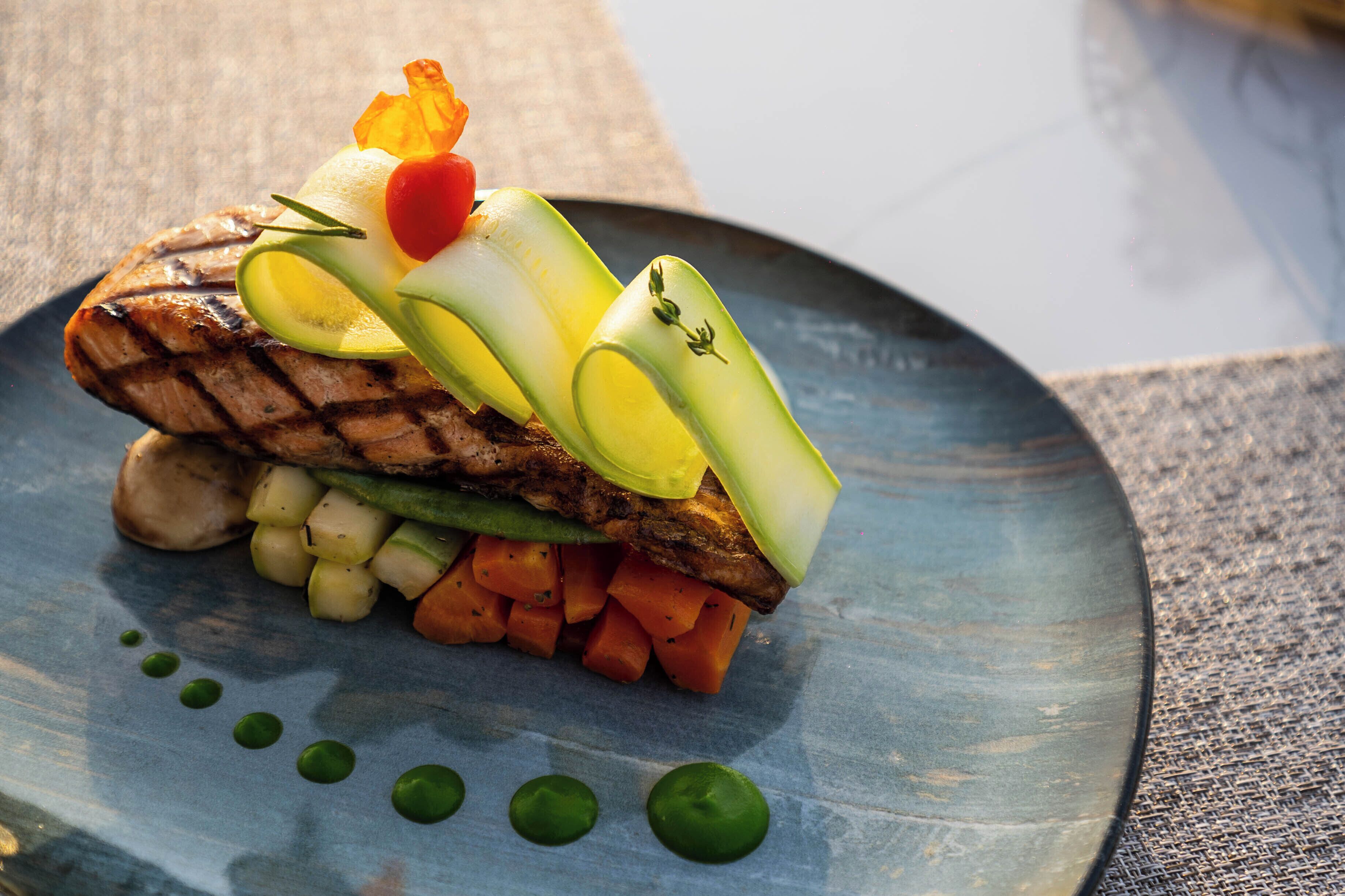A plate with grilled meat, vegetables, and a decorative garnish.
