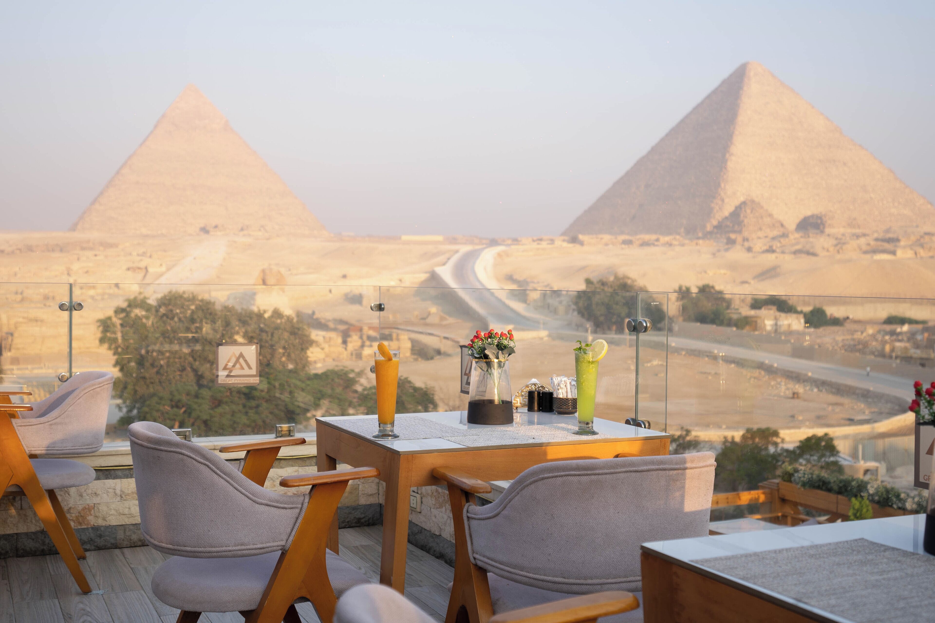 A table with drinks and a vase of flowers, overlooking the pyramids.