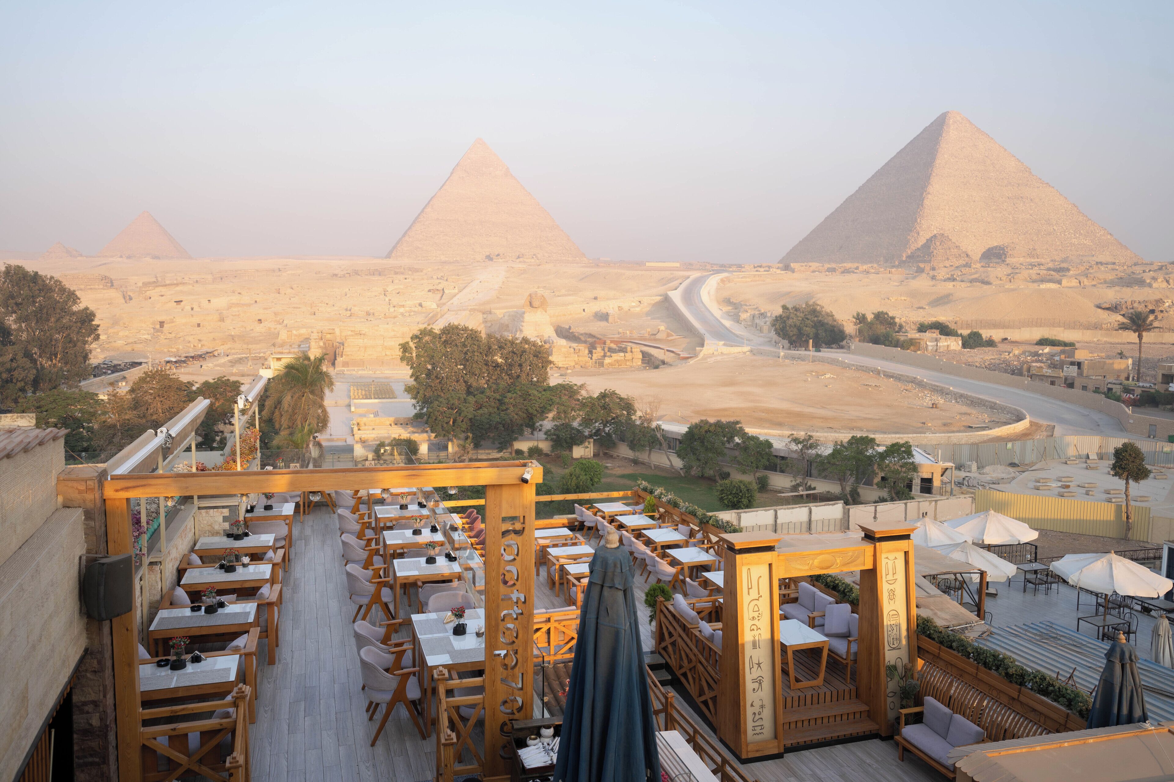 An outdoor dining area with tables and chairs, overlooking the pyramids.