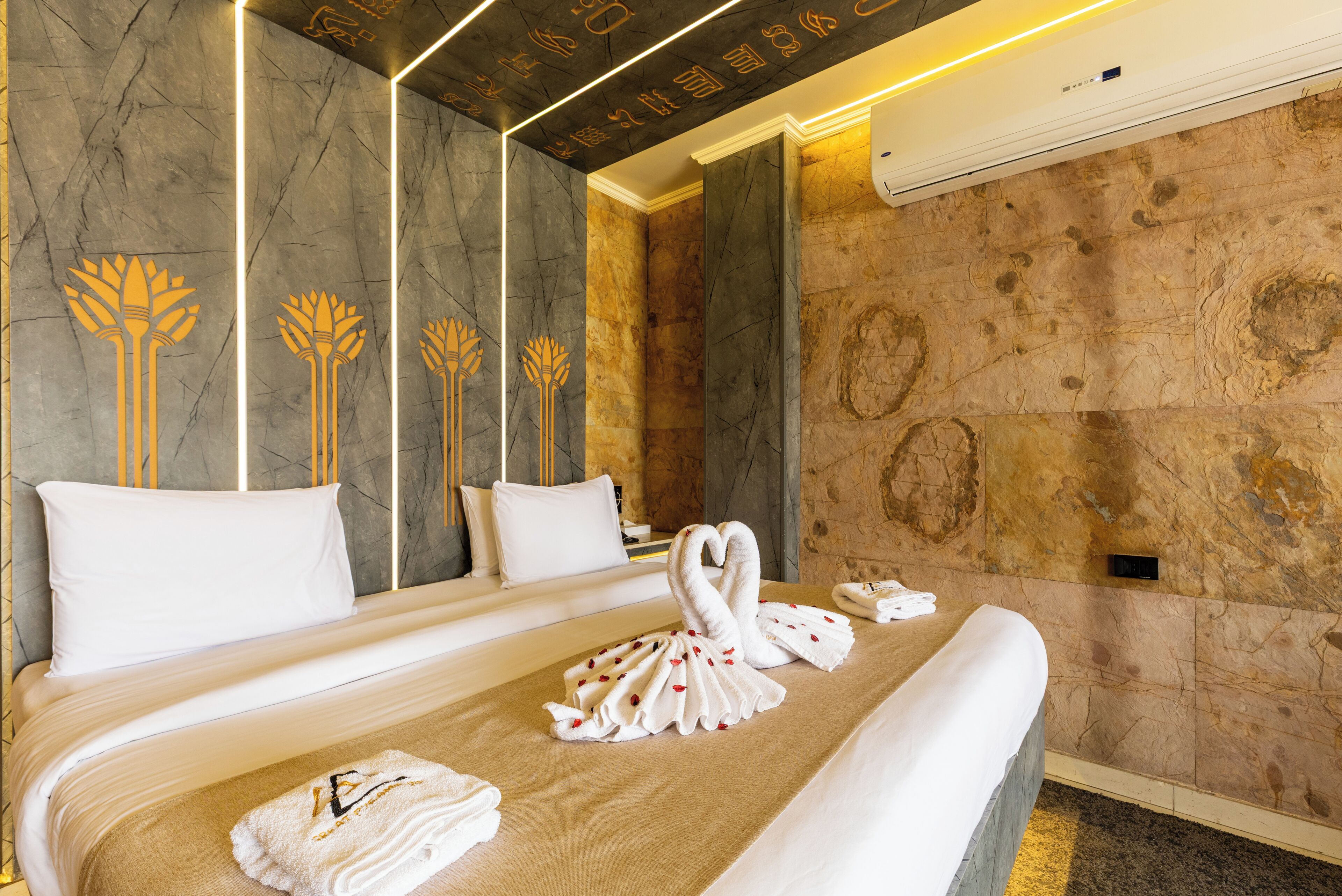 Una habitación de hotel con una cama grande, una pared con textura similar al mármol y un techo de diseño moderno.