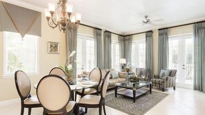 A spacious living room with a dining area, a chandelier, and large windows with curtains. - Condo Terrace Breeze 3 Bedroom Reunion (Kissimmee)