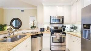 A modern kitchen with white cabinets, stainless steel appliances, and a granite countertop. - Condo Terrace Breeze 3 Bedroom Reunion (Kissimmee)