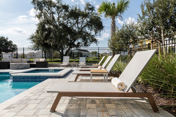 Un área junto a la piscina con sillones de descanso, una piscina pequeña y un deck de hormigón.