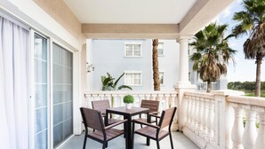 A balcony with a table and chairs, a potted plant, and a view of a building and palm trees. - Condo Serenity at Cabana Court 3 Bedroom Reunion (Kissimmee)