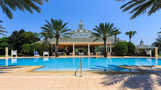 A swimming pool with a covered area and palm trees. - Condo Serenity at Cabana Court 3 Bedroom Reunion (Kissimmee)