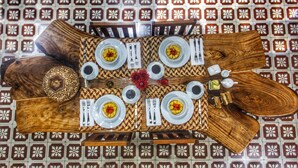 Une table à manger dressée avec des assiettes, des couverts et des verres, entourée de chaises et surmontée d’un sol à motifs.