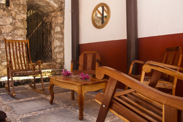 A stone wall with a wooden bench and a table with purple flowers.