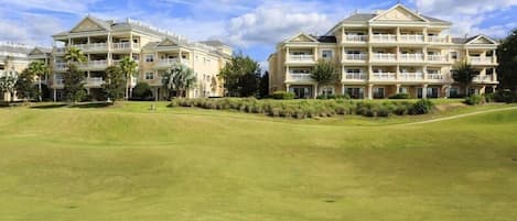 A multi-story hotel with a flat roof, multiple balconies, and a well-maintained lawn in front.