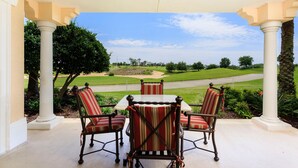 A covered patio with a table and chairs, overlooking a golf course. - Condo Centre Court Sun 3 Bedroom Reunion (Kissimmee)