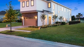 Une maison moderne à deux étages, dotée d’un garage, d’une pelouse bien entretenue et surplombant un ciel dégagé.