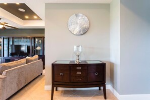 A modern living room with a dark wood cabinet, a glass-top coffee table, and a large decorative plate on the wall. - Villa Grande View 6 Bedroom Reunion (Kissimmee)
