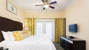 A hotel room with a bed, a desk, a television, and a ceiling fan. - Condo Hertitage Crossing Modern Delight 3 Bedroom Reunion (Kissimmee)