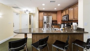 A modern kitchen with a central island, stainless steel appliances, and wooden cabinets. - Condo Hertitage Crossing Modern Delight 3 Bedroom Reunion (Kissimmee)