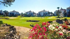 A golf course with a clubhouse and residential buildings in the background. - Condo Hertitage Crossing Modern Delight 3 Bedroom Reunion (Kissimmee)