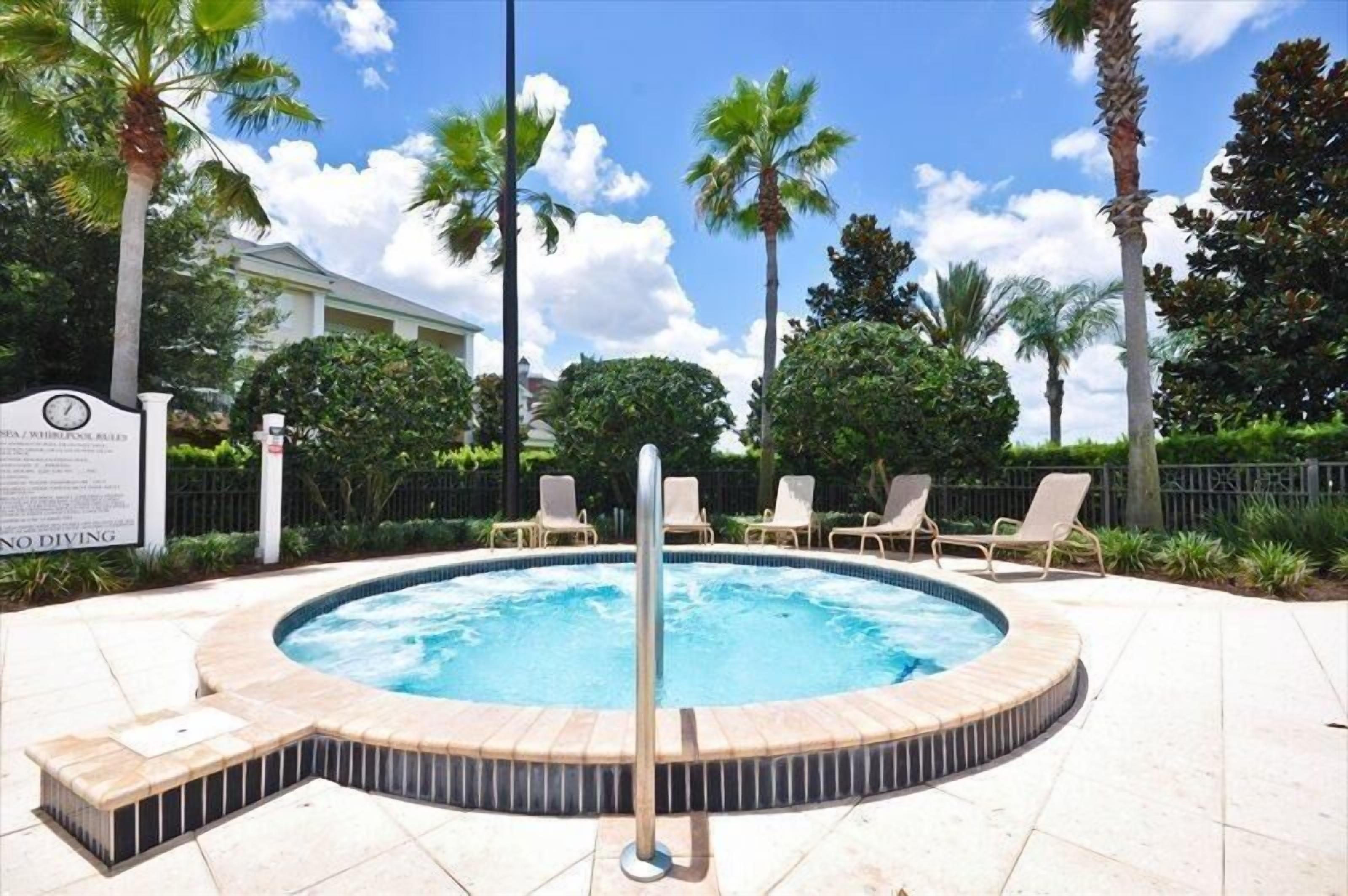 A hot tub surrounded by palm trees and lounge chairs, with a sign indicating no diving.