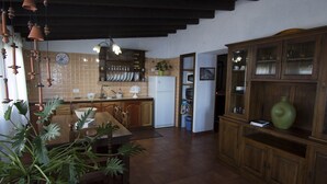 A kitchen with wooden cabinets, a refrigerator, and a dining table with chairs. - Casa Rural Sofia (Hermigua)