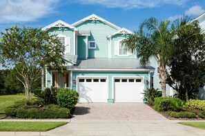 A two-story house with a garage, surrounded by well-maintained landscaping and trees.