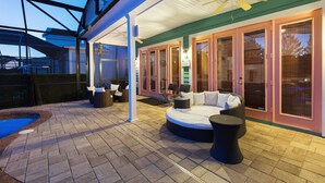 Un patio exterior cubierto con piscina, zona de estar y puertas corredizas de vidrio.