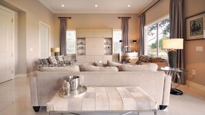 Un salon moderne avec un canapé beige, une table basse en verre et un coin repas comprenant une petite table et des chaises.