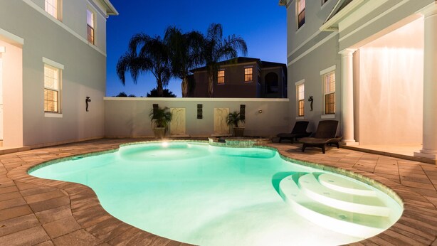 Une piscine à bord incurvé, entourée d’une terrasse en pierre.