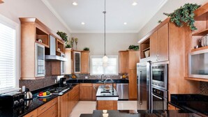 Une cuisine moderne avec des meubles en bois, des appareils électroménagers en acier inoxydable et un plan de travail en granit noir.