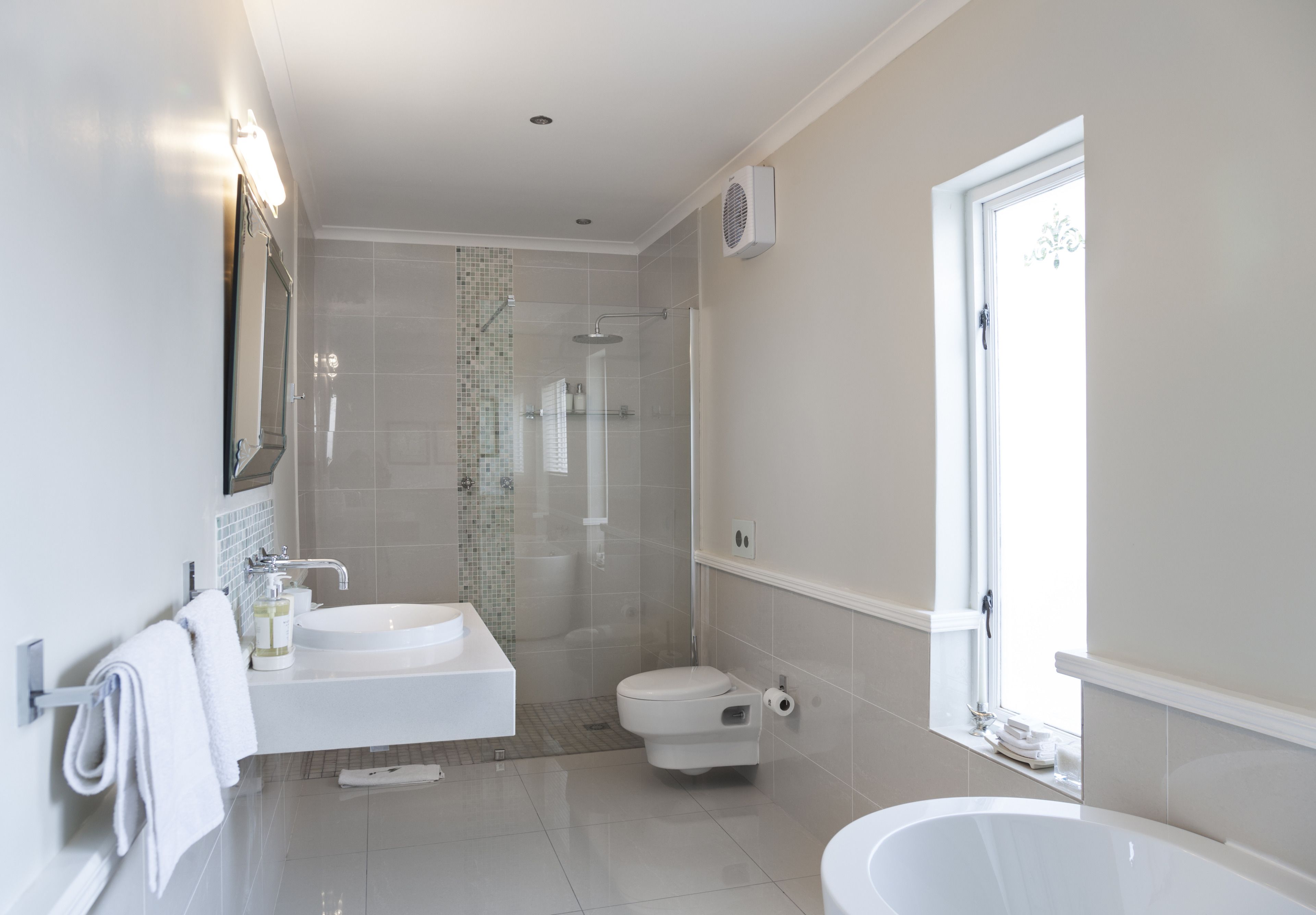 A modern bathroom with a shower, toilet, sink, and bathtub.
