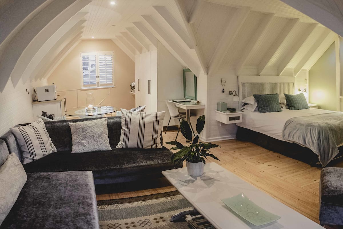 Ein gemütliches Schlafzimmer im Loft-Stil mit Bett, Schreibtisch und einer Sitzecke.