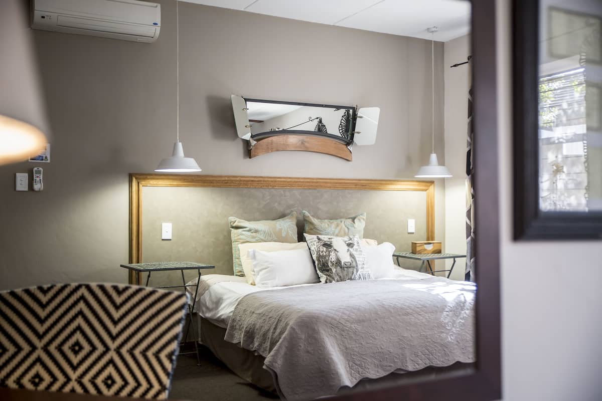 Ein Hotelzimmer mit einem Bett, Nachttischen, einem Wandbild und einem Fenster.