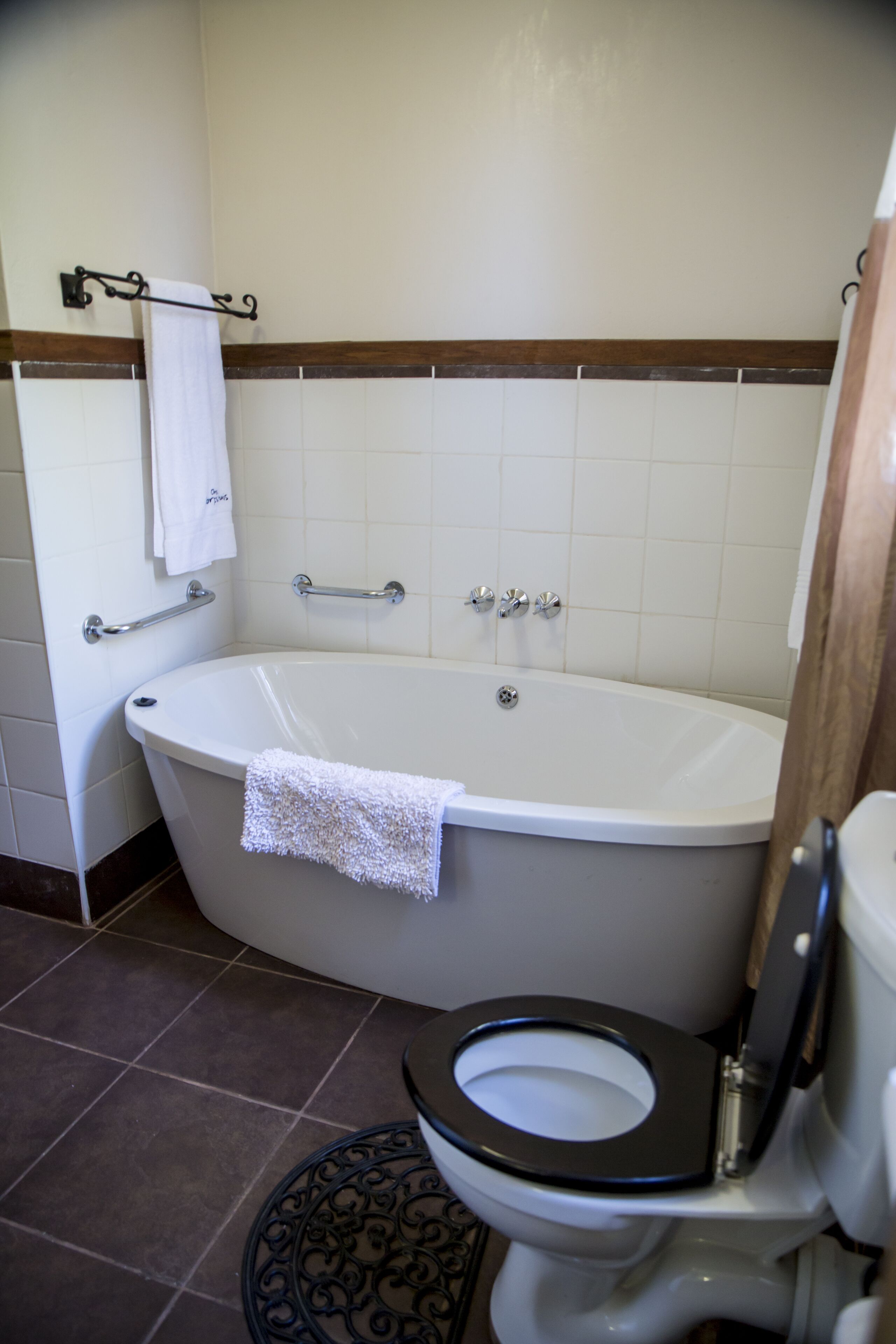 Un baño con bañera, inodoro y un perchero para toallas.