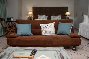 Un canapé marron avec deux coussins bleus, une télécommande et un objet décoratif posé sur une table basse.